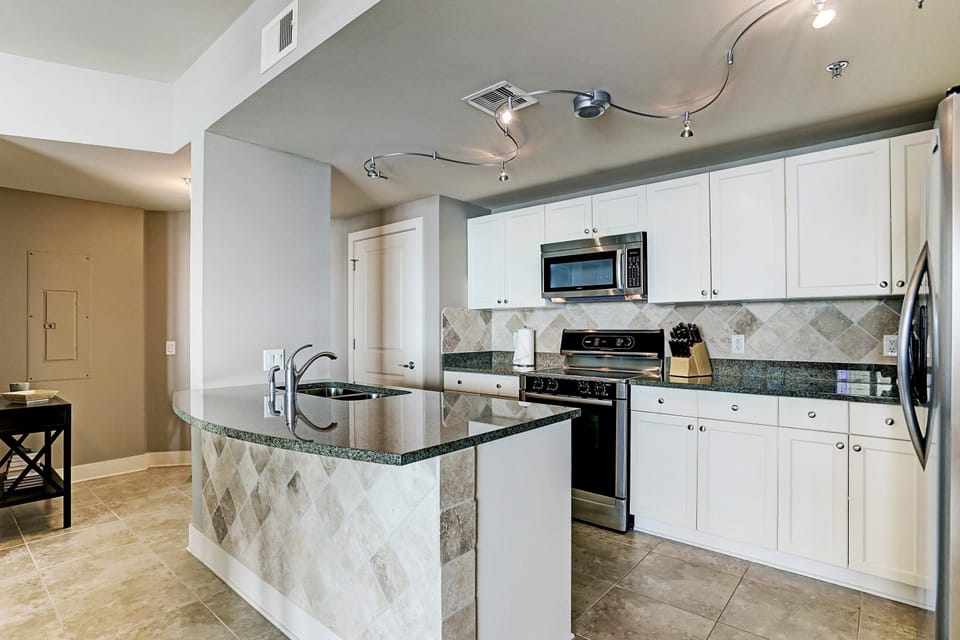 Modern kitchen features granite countertops, stainless steel appliances, tile backsplash, and an eat-in bar—perfect for entertaining or enjoying casual meals.