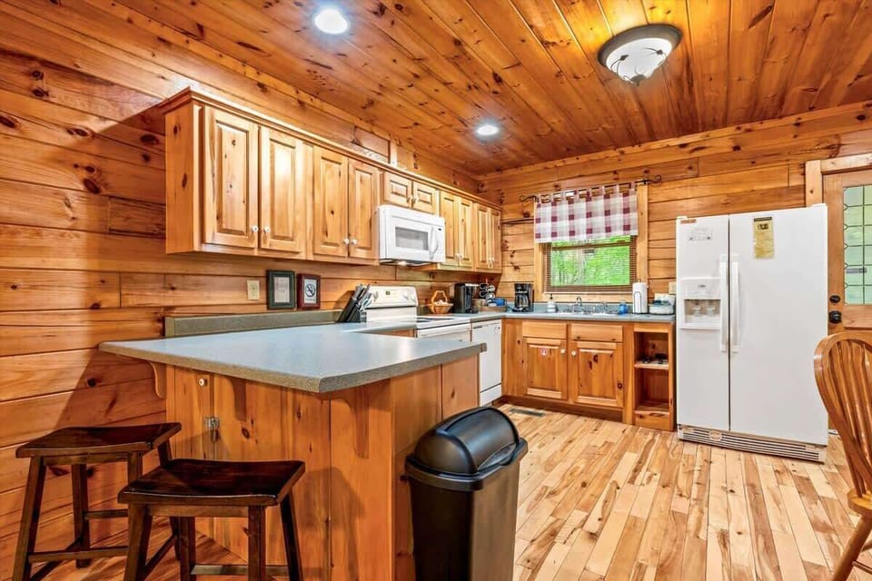 Cook and dine with ease in the spacious kitchen, complete with bar seating, full-size appliances, and charming wood finishes that create a warm, rustic ambiance.