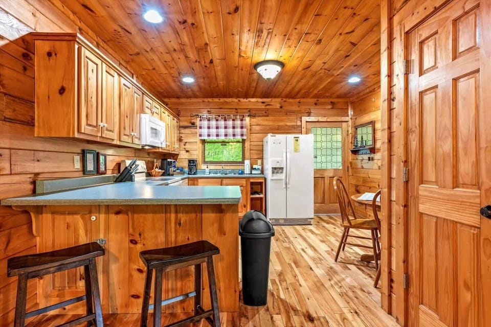 The fully equipped kitchen features warm wood cabinetry, modern appliances, and a cozy dining nook—perfect for preparing meals and enjoying coffee with a view.