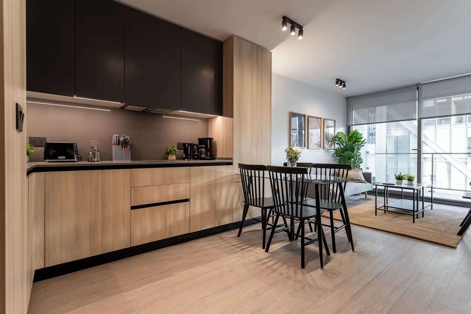 Experience modern living in this stylish kitchen, featuring sleek cabinetry and a cozy dining area bathed in natural light.