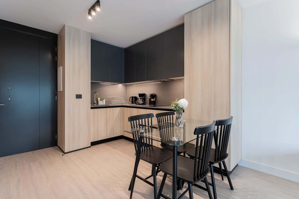 Experience modern living in this stylish kitchen, featuring sleek cabinetry and a cozy dining area perfect for meals and gatherings.