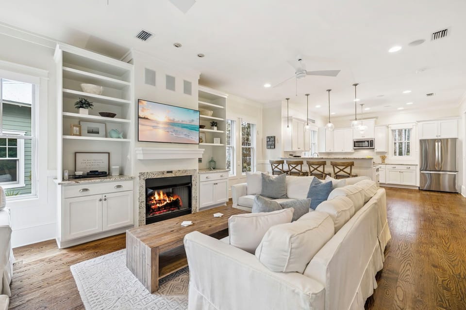 Unwind in your open-concept living space where coastal comfort meets modern elegance, featuring a crackling fireplace and seamless flow to the gourmet kitchen.
