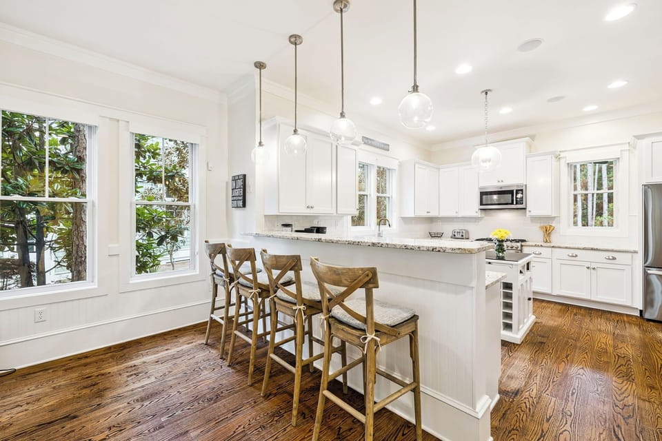 Your bright, modern kitchen flows with white cabinetry, granite counters, and rustic wood floors perfect for cooking memorable meals.