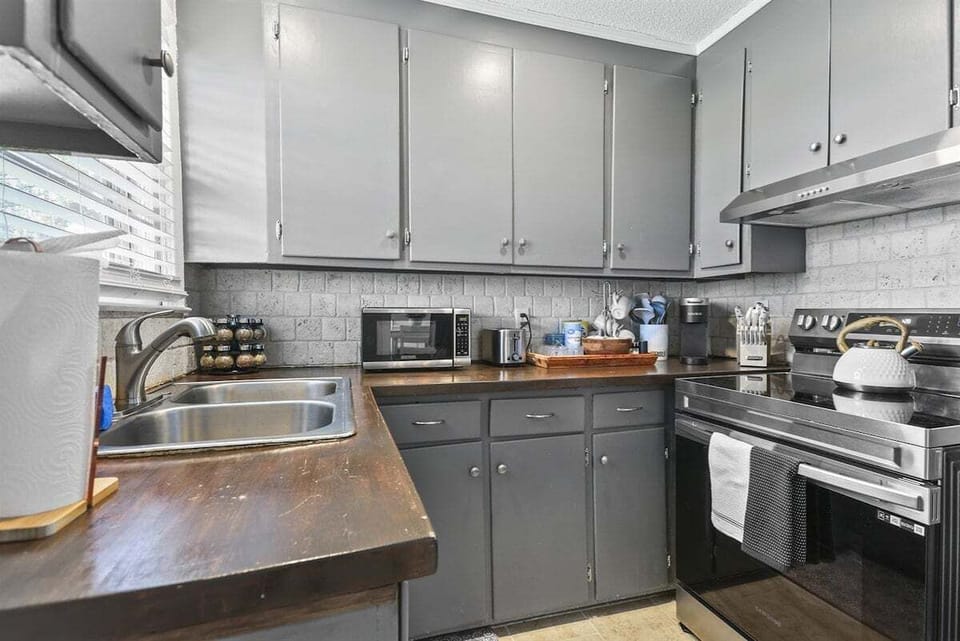 The kitchen blends style and function with its warm wood countertops, modern appliances, and cozy charm.