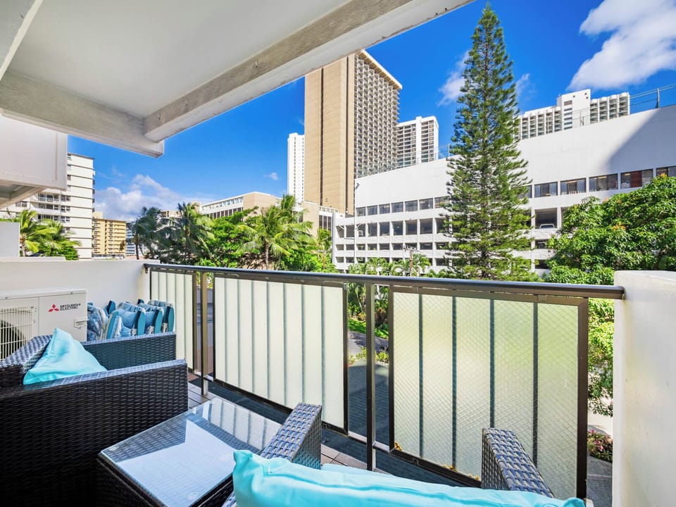 Balcony for Living Room - Guest-Facing Caption: Take a breath of fresh island air. Your lana/balconyi frames Waikiki’s skyline, a sunny perch for reading, chatting, and easing into the day.