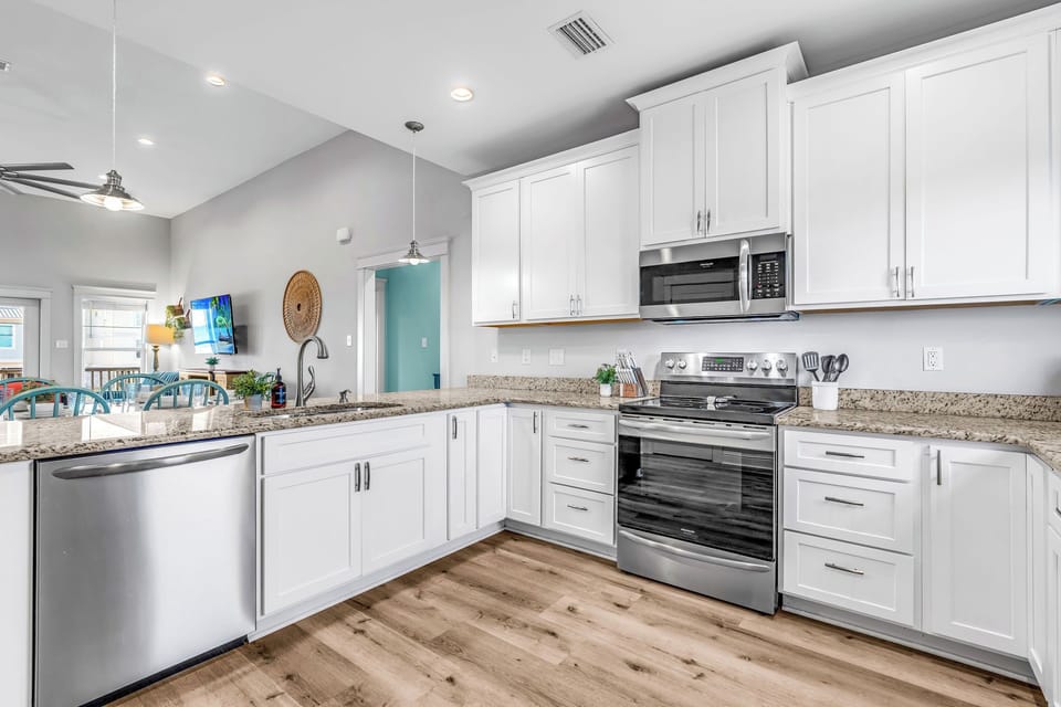Spacious open kitchen w/ stainless steel appliances, well stocked to make meals.