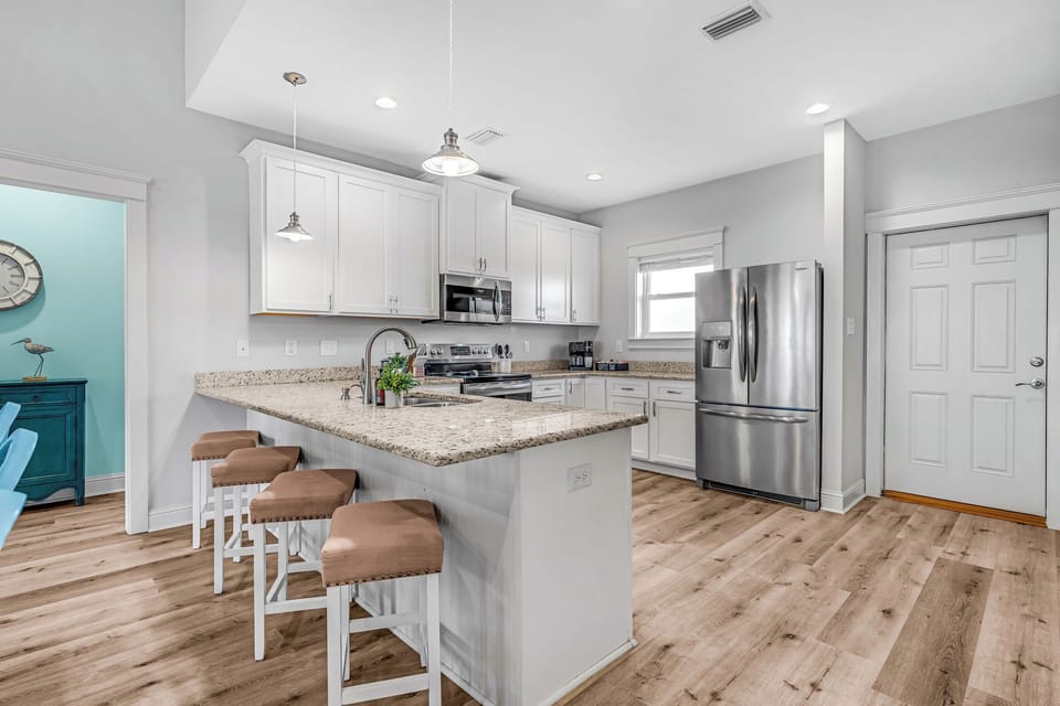 Spacious open kitchen w/ stainless steel appliances, well stocked to make meals.