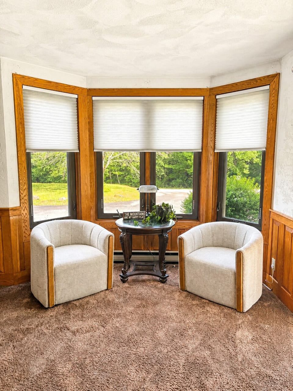 Charming bay-window seating nook with cozy chairs and serene nature views