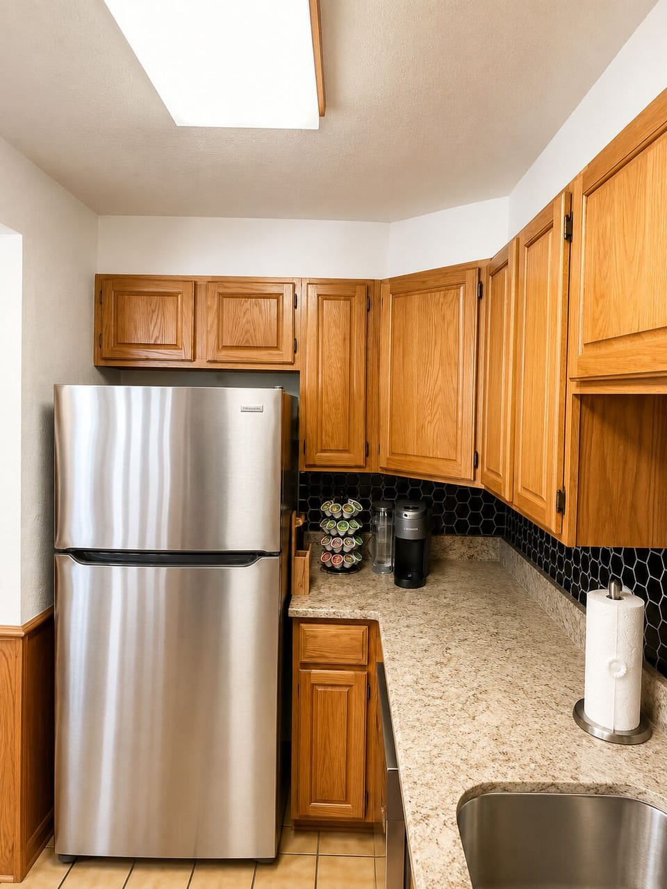 Bright kitchen with stainless fridge, coffee station, and ample counter space