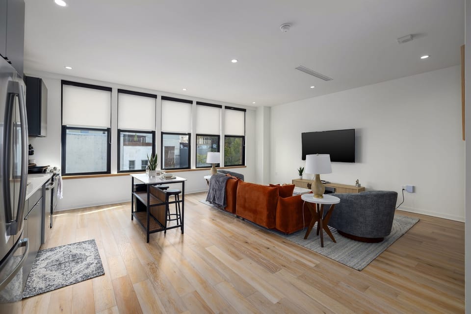 Open-concept living—this spacious living area features floor-to-ceiling windows for natural light, a plush sofa for ultimate relaxation, and a fully equipped kitchen for culinary freedom.