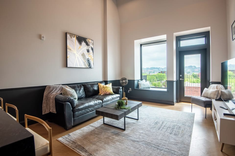 Relax in style in our chic living room, boasting a luxurious black leather couch with gold accents, perfect for unwinding or streaming your favorites on the smart TV.