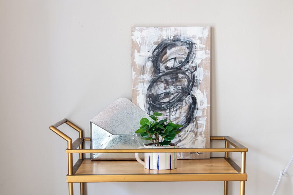 Elegant bar cart featuring modern decor and an abstract art piece from a local artist for a stylish accent