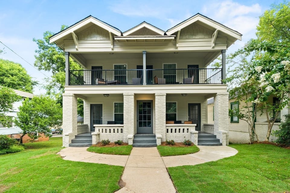 A picturesque view of the Avenue Quads showcasing its charming architecture and welcoming front porches surrounded by lush greenery.
