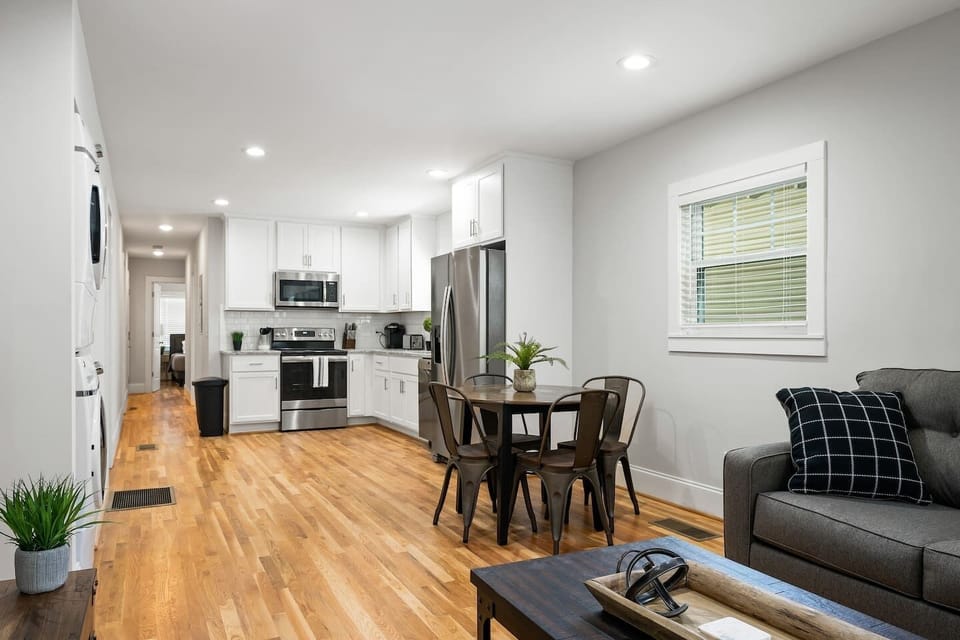 This open-concept area combines stylish living space with a dining setup for four, framed by large windows that enhance the airy feel.