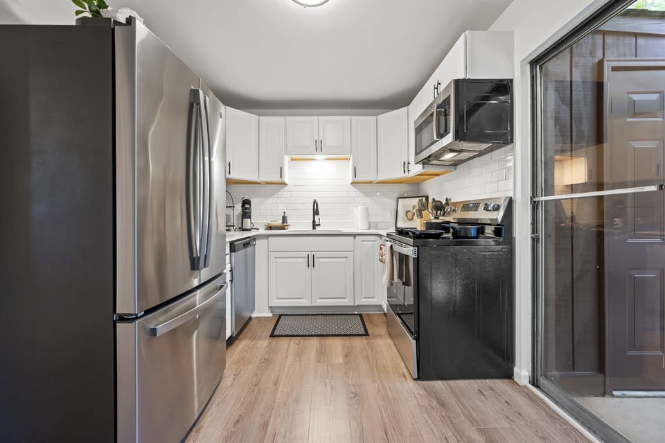 The cozy living room, filled with plush seating and vibrant artwork, seamlessly transitions into a modern kitchen featuring sleek countertops and stainless steel appliances. From there, step onto the inviting patio, perfect for relaxing or dining al fresco