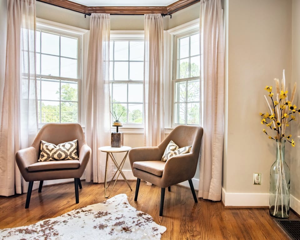 The living room features a cozy reading nook with two comfy chairs perched by the front windows. Message us about our concierge services and locally curated experiences  