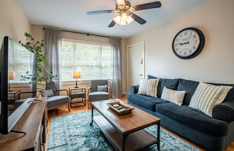 Bright and cozy living room featuring a comfy sofa, wall clock, and beautiful natural light.