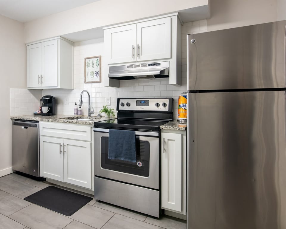 Modern kitchen setup with stainless steel appliances, including oven, fridge, and coffee maker.