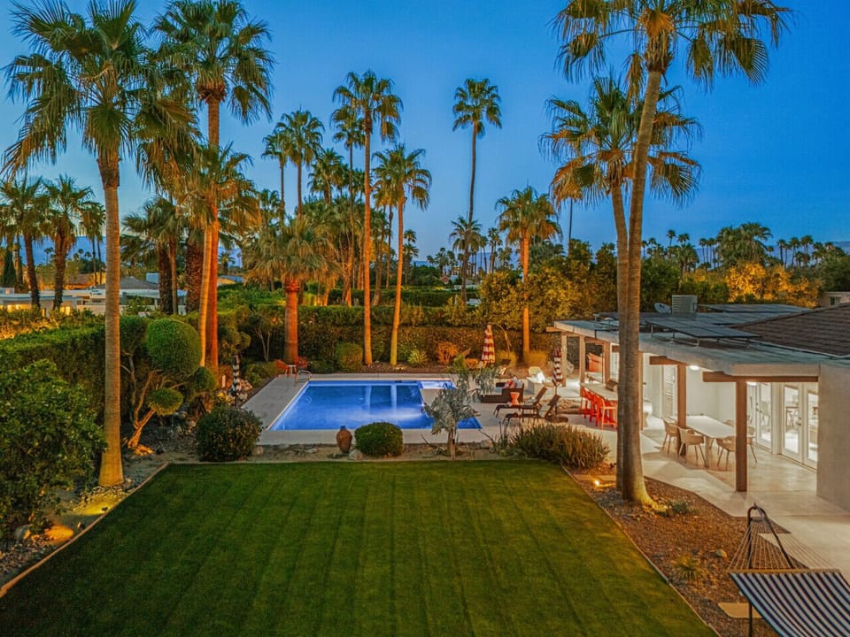 Aerial-style view of the pool oasis surrounded by tall palms & desert landscaping.