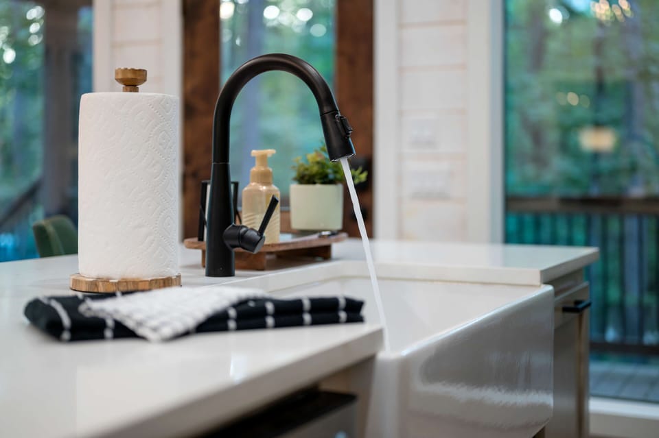 Modern kitchen sink with sleek black faucet and natural lighting.