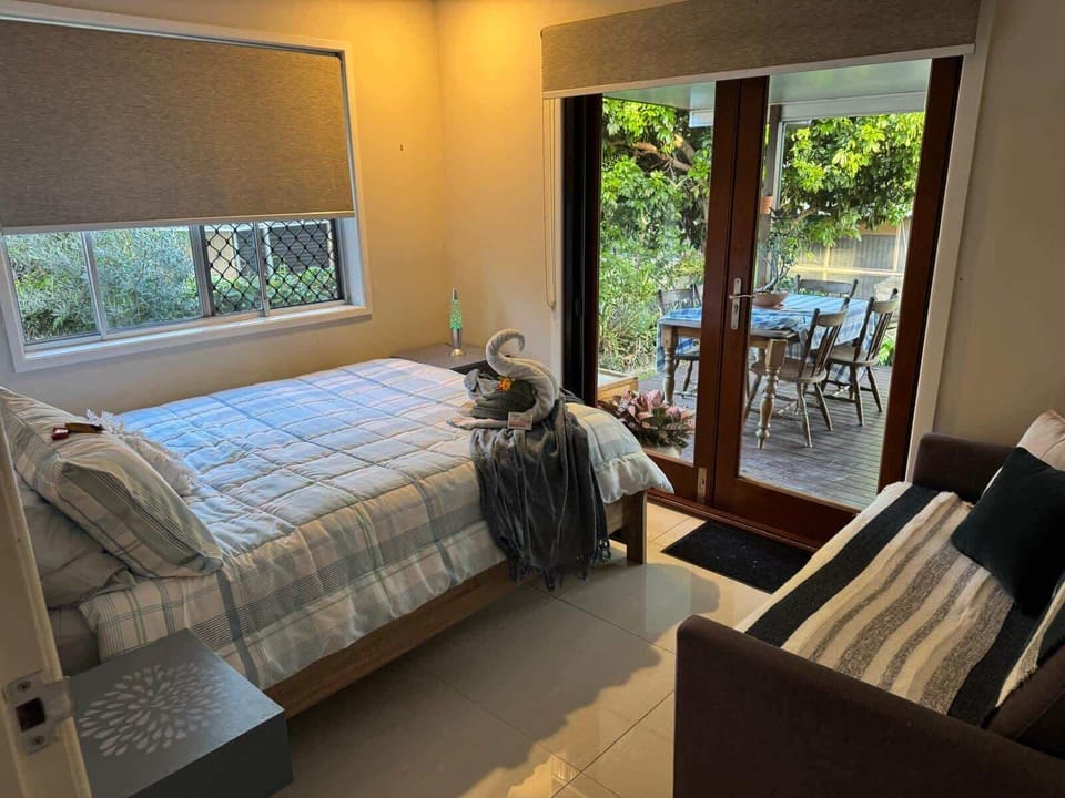 Double bed with air con - wake to peaceful views through french doors across the deck, back yard and park beyond.