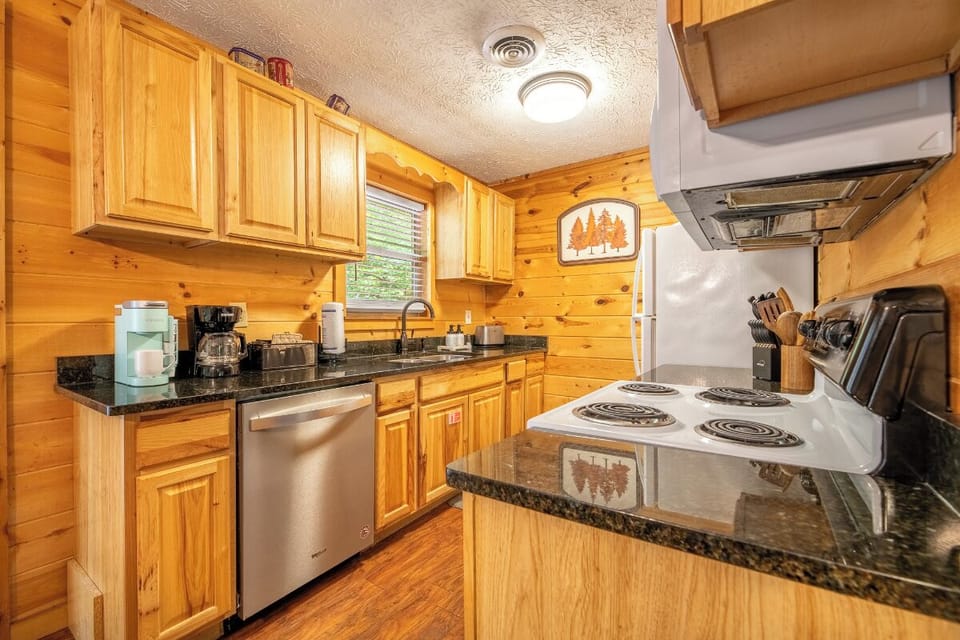Your fully-equipped kitchen features warm wood cabinetry, granite countertops, and modern appliances including a dishwasher—perfect for preparing your favorite meals during your mountain getaway.
