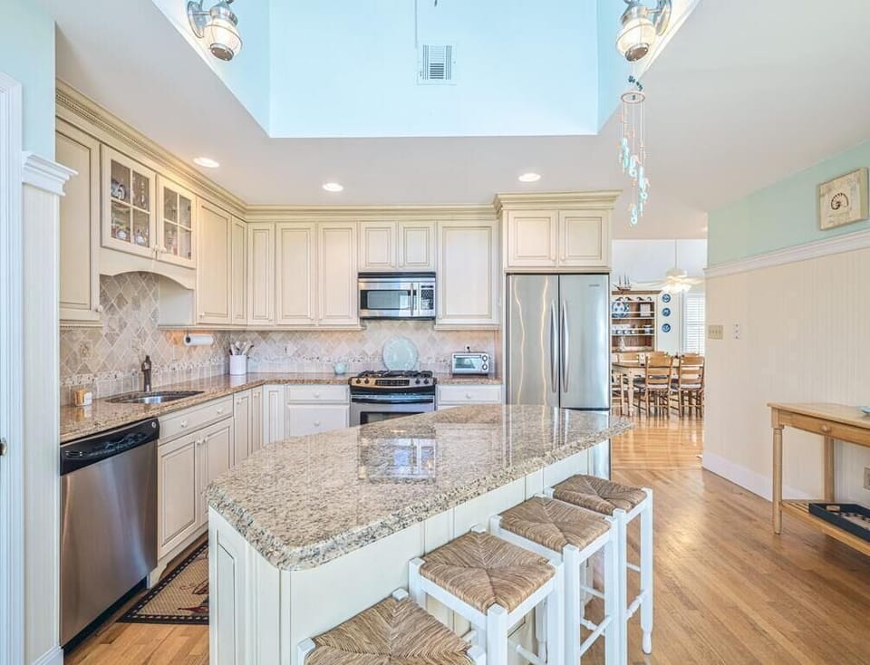 Gather around the stylish granite island in the heart of this lovely kitchen, where coastal charm meets functionality, making it ideal for both casual breakfasts and culinary creations.