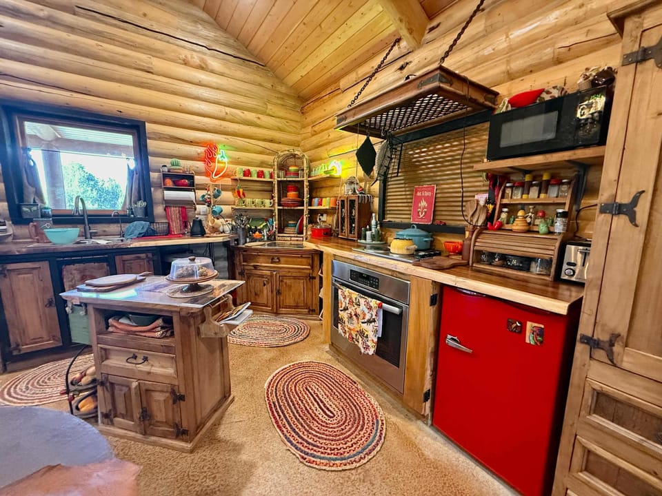 The cute and charming kitchen features a mini fridge, microwave, stove top and oven.