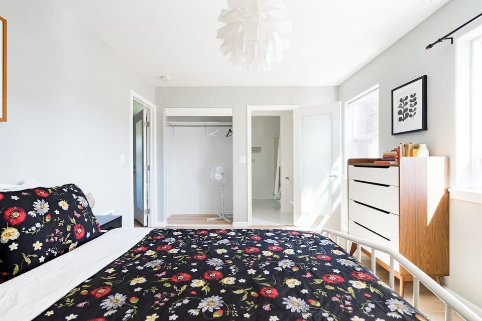 Bedroom with bold floral bedding and dresser storage.