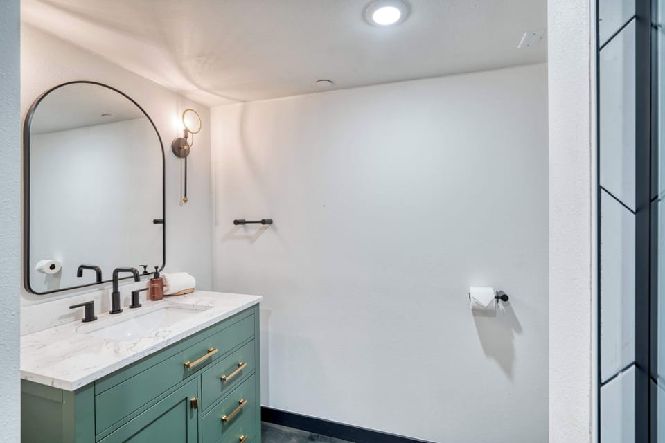 Bathroom vanity with green drawers and a wall mirror.