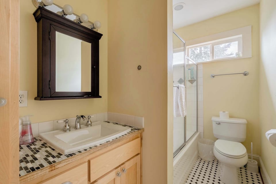 Bathroom vanity and toilet with a glass shower beyond.