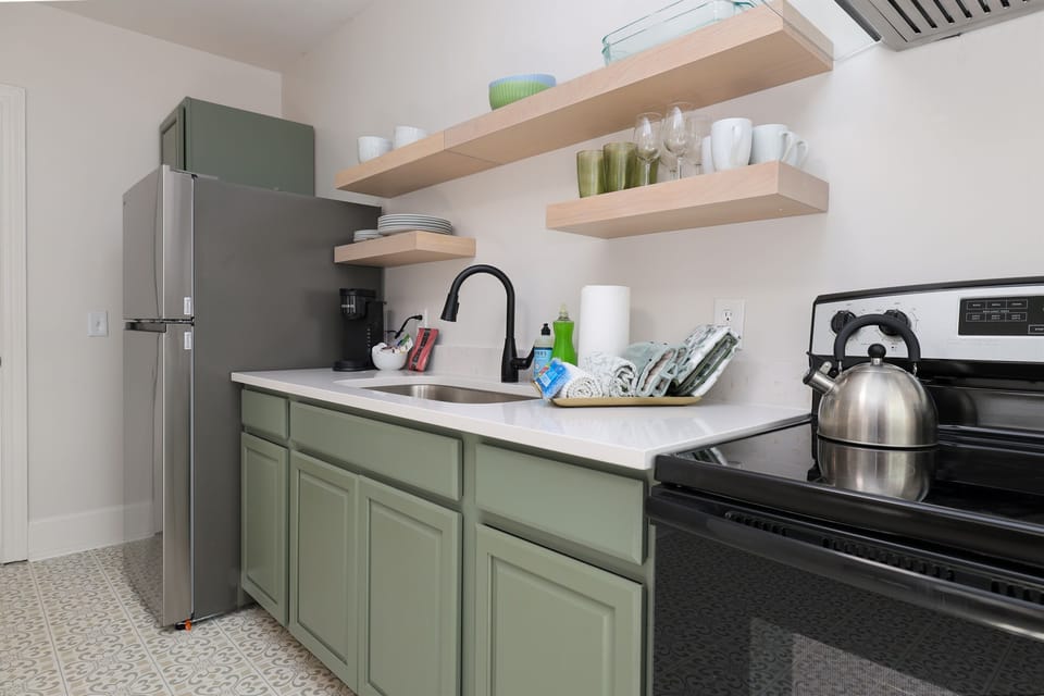 Newly renovated kitchen with floating shelves, stainless steel stove and refrigerator.