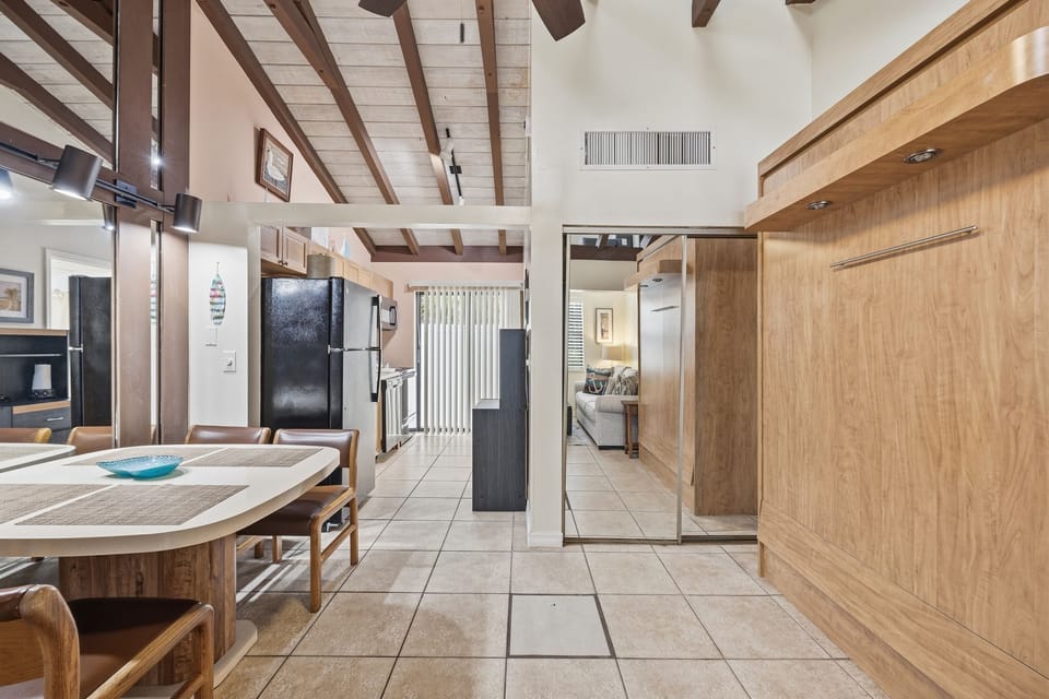 An open studio layout features exposed beams, tiled floors, and a functional kitchen setup for comfortable beachfront living.