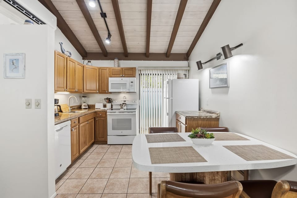 The dining area includes a round table with seating, conveniently located beside the fully equipped kitchen.