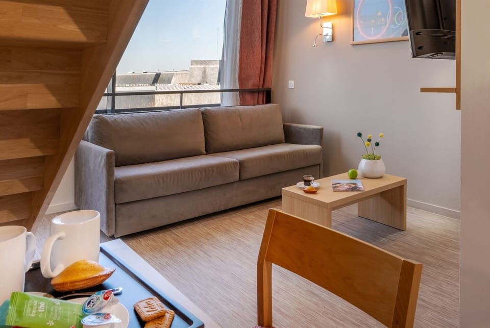 This inviting space showcases a grey sofa, a wooden coffee table laden with snacks, and a warm atmosphere from the lighting.