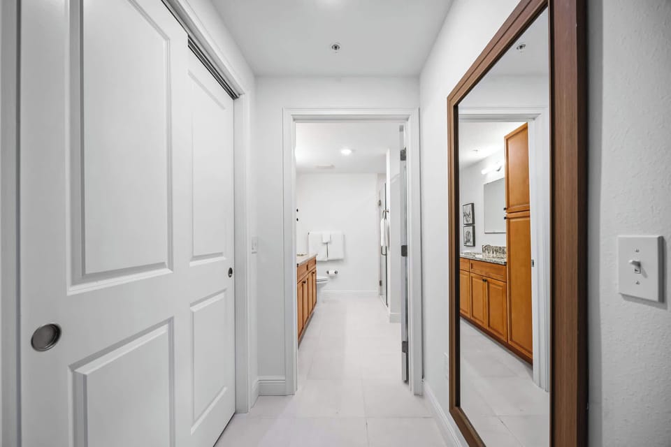 Hallway with a large wooden-framed mirror leading to a bathroom with wooden cabinetry.
