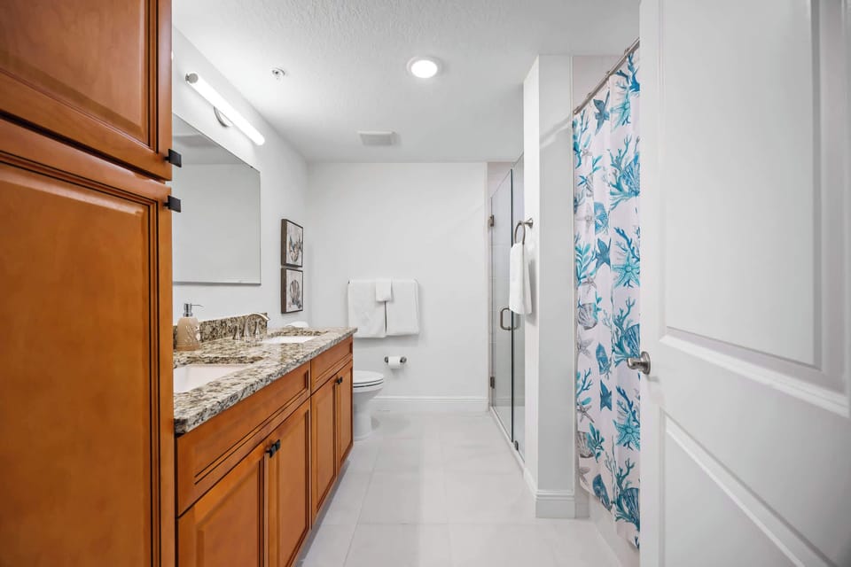 Modern bathroom with granite countertop and a shower featuring a blue sea life curtain.