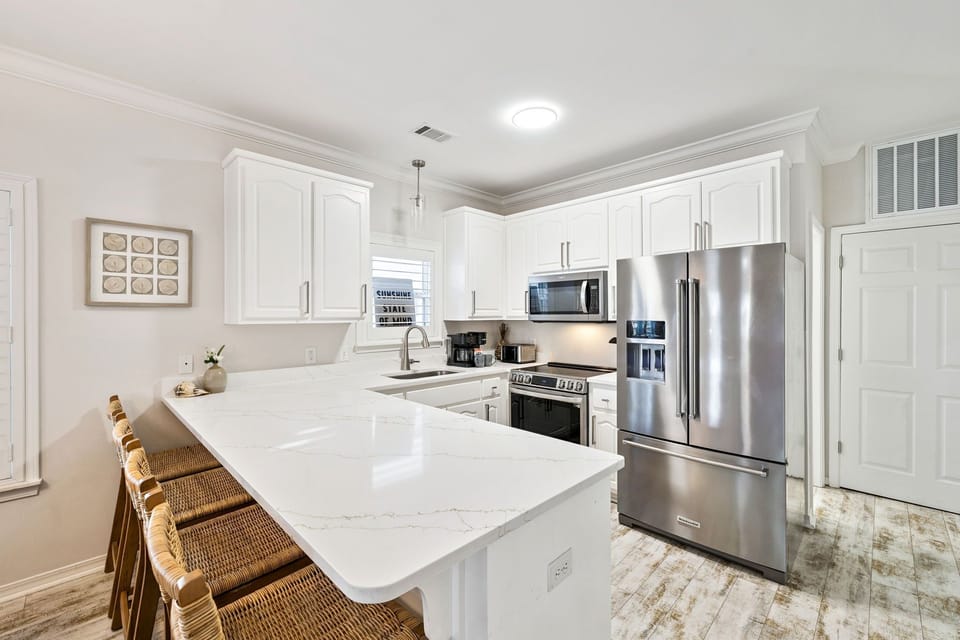 Your elegant kitchen features pristine white cabinetry, gleaming quartz countertops, and top-tier stainless steel appliances for effortless meal preparation.