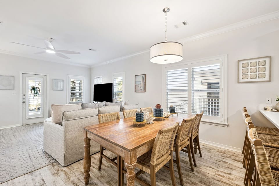 Your open-concept living space flows beautifully with rustic dining table, cozy sectional, and bright windows creating the perfect gathering spot.