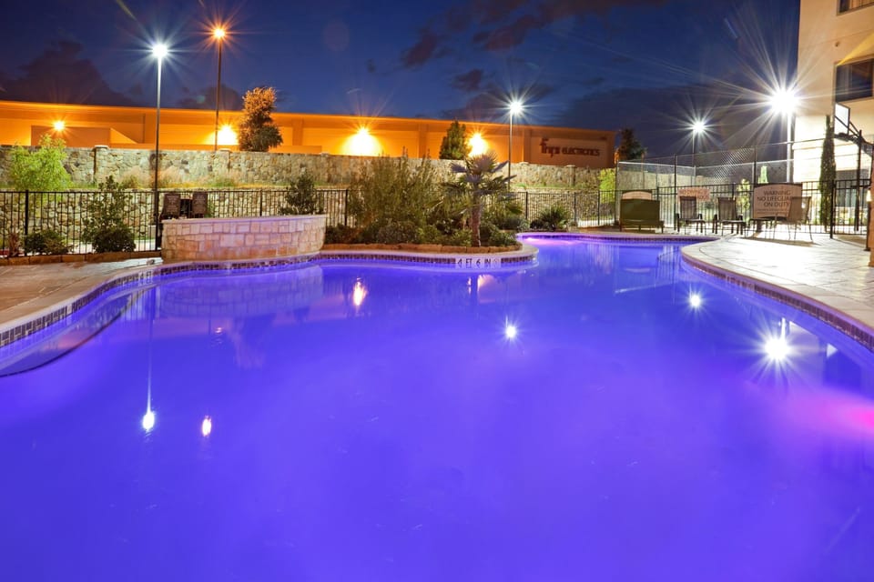 Outdoor pool illuminated at night with ambient lighting