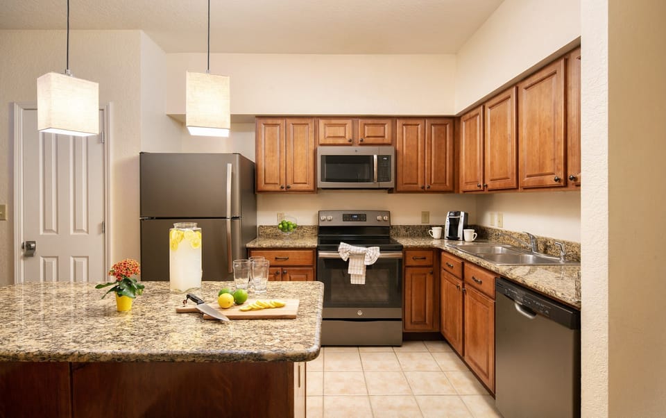 Full kitchen with wooden cabinetry, stainless appliances, island seating, and a Keurig on the counter