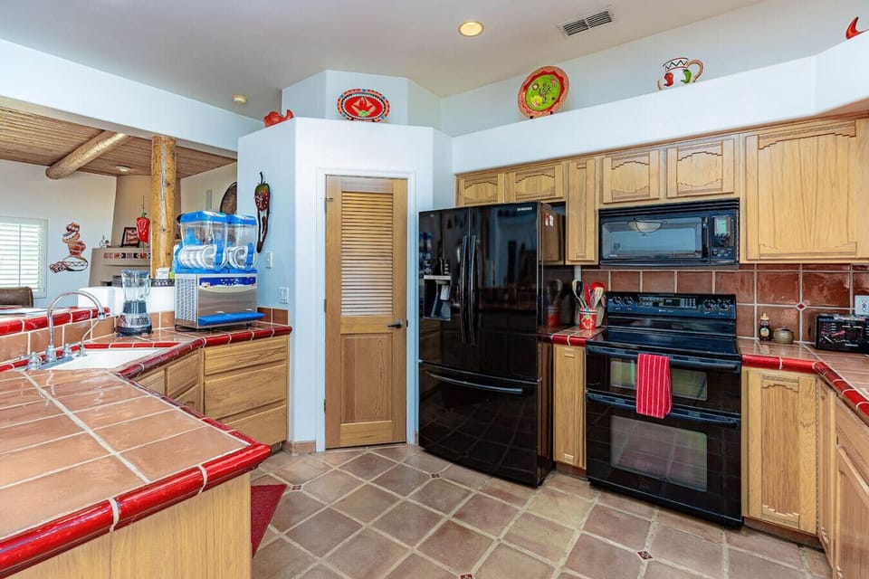 Fully stocked kitchen with pots, pans, utensils, a Keurig/drip coffee maker, and counter seating for tw
