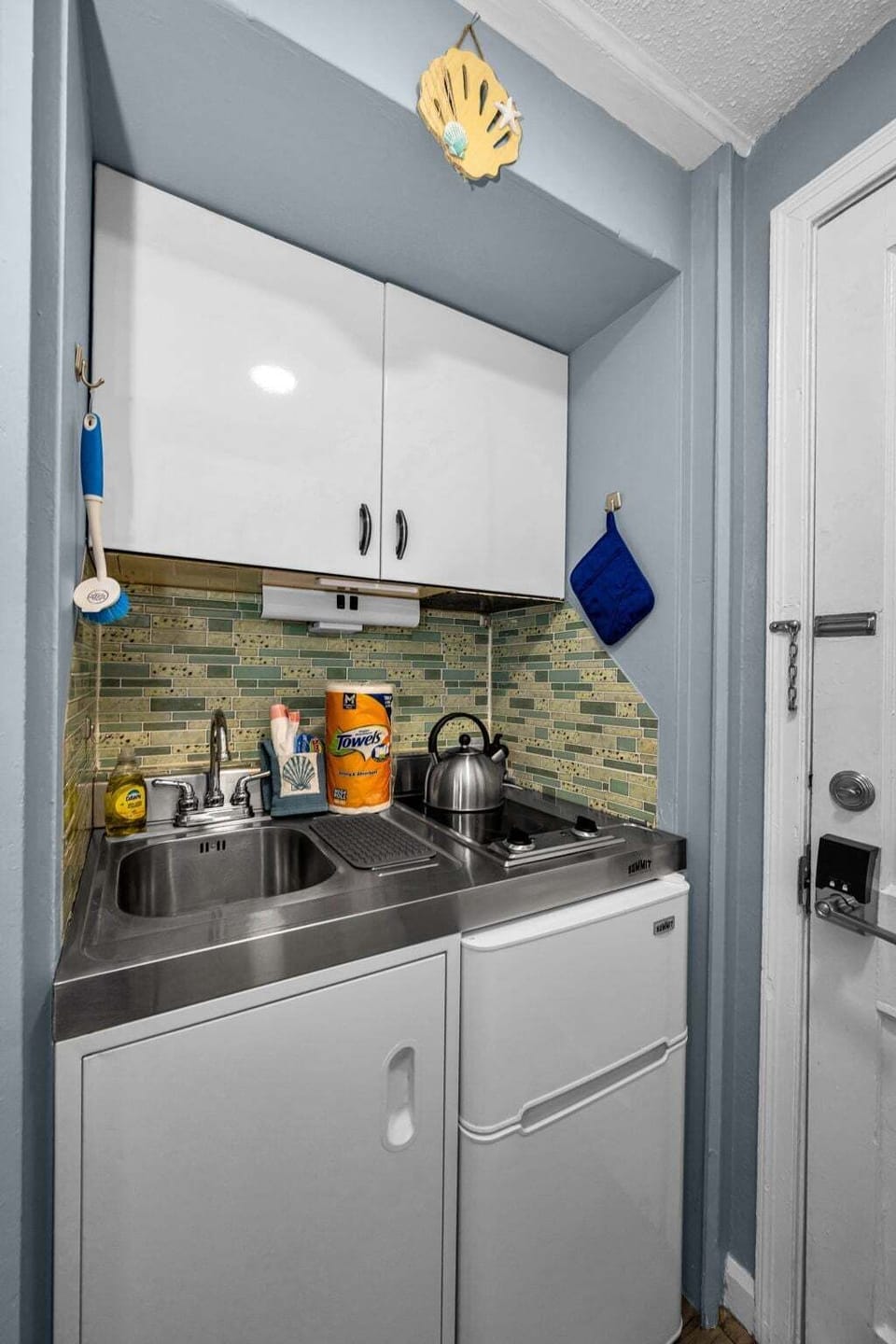 A compact but functional kitchenette with a two-burner stovetop, sink, and mini fridge — ideal for whipping up quick meals between beach trips.