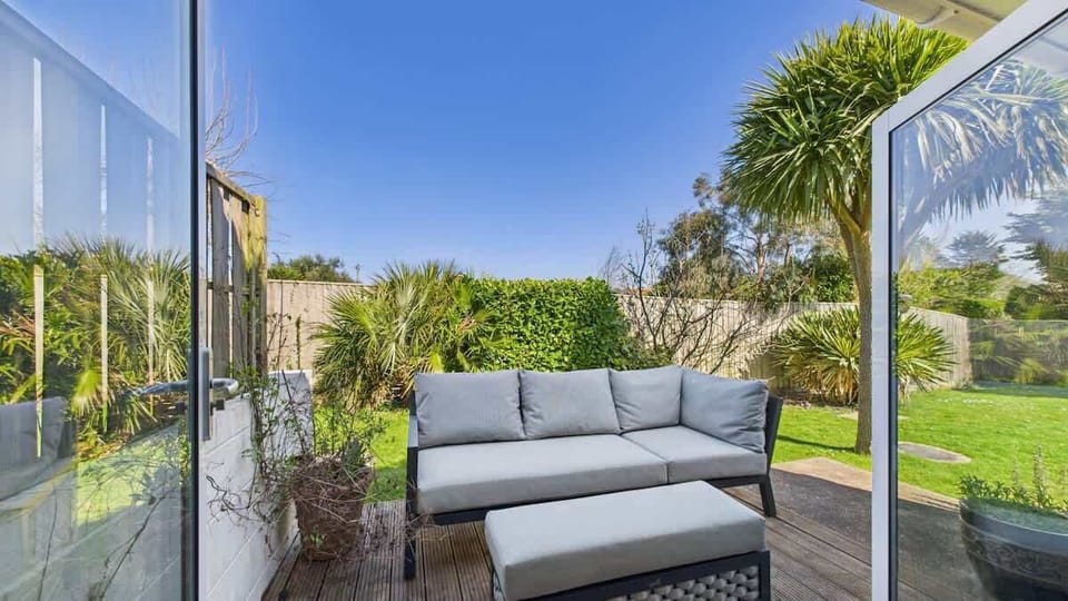 The private, fully enclosed rear patio features comfortable outdoor lounge furniture, perfect for relaxing.