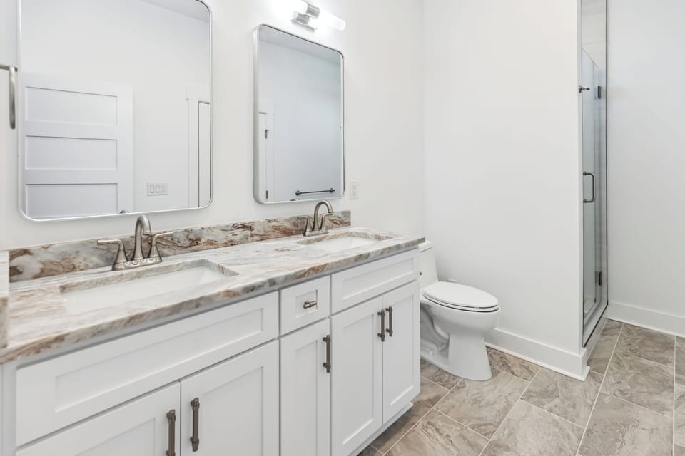 Freshen up in your pristine bathroom featuring elegant marble countertops, dual vanities, and a spacious walk-in shower.