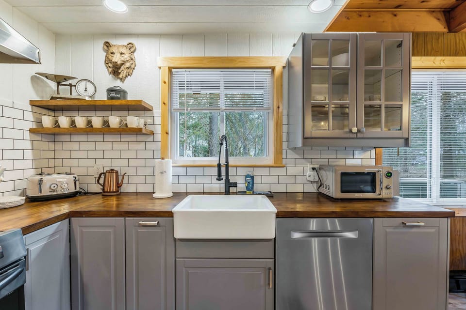 This cozy kitchen combines sleek, modern appliances with charming retro touches - like a vintage-inspired toaster and kettle - set against warm wood countertops and classic subway tile for a perfect blend of old and new.