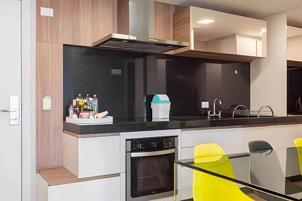 Cozinha com fogão e forno, exaustor, tempero, escorredor e mesa 6 cadeiras.