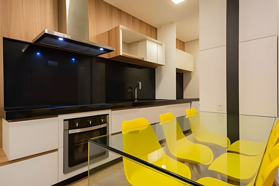 Cozinha equipada com exaustor, fogão de indução, forno, pia, armários e mesa 6 cadeiras.