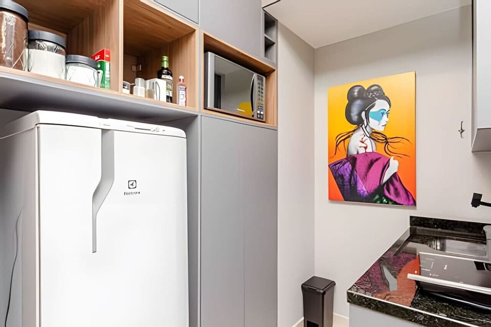 Cozinha com geladeira, temperos, micro-ondas, pia e cooktop.