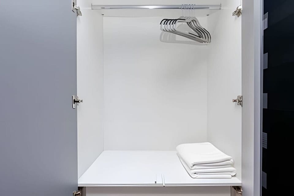 Armário com cabides para roupas e roupas de cama.